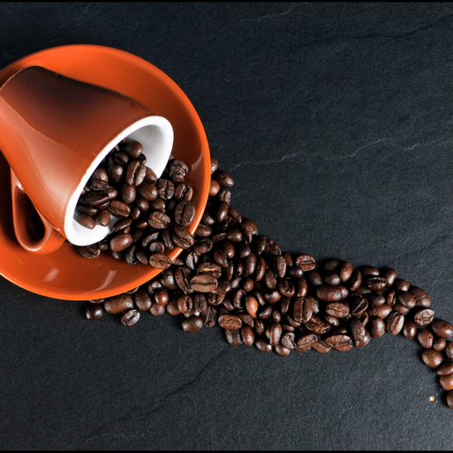 100% colombian coffee beans spilling from a mug
