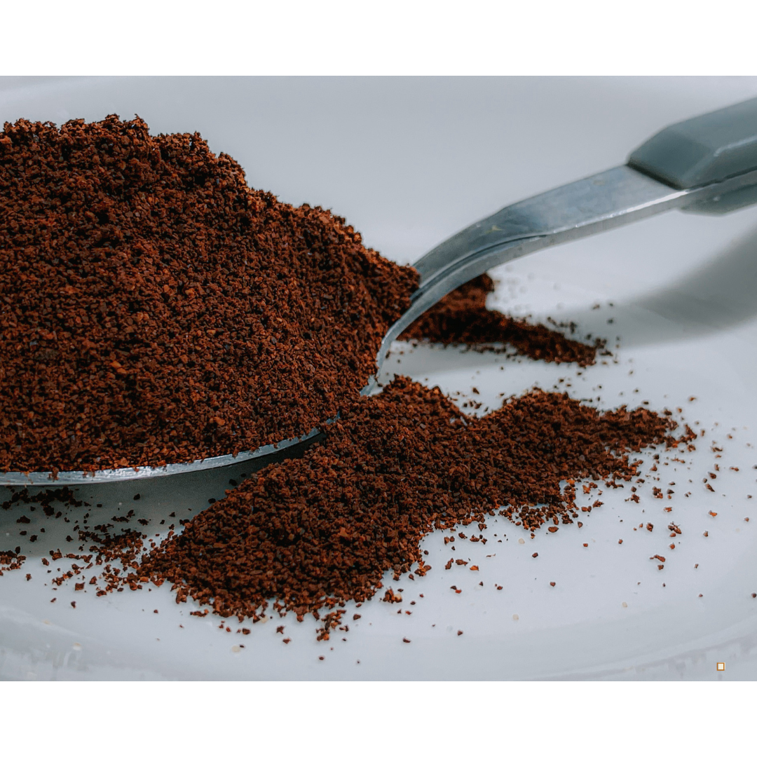 decaf ground coffee in a spoon on a white table top