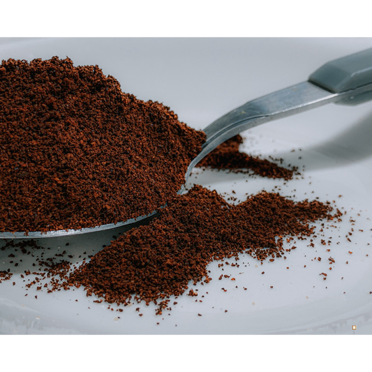decaf ground coffee in a spoon on a white table top