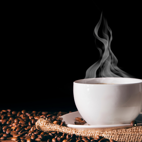 italian roast coffee beans with steaming mug of coffee