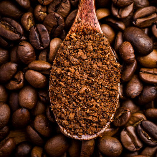light roast decaf ground coffee in a wooden spoon with whole coffee beans