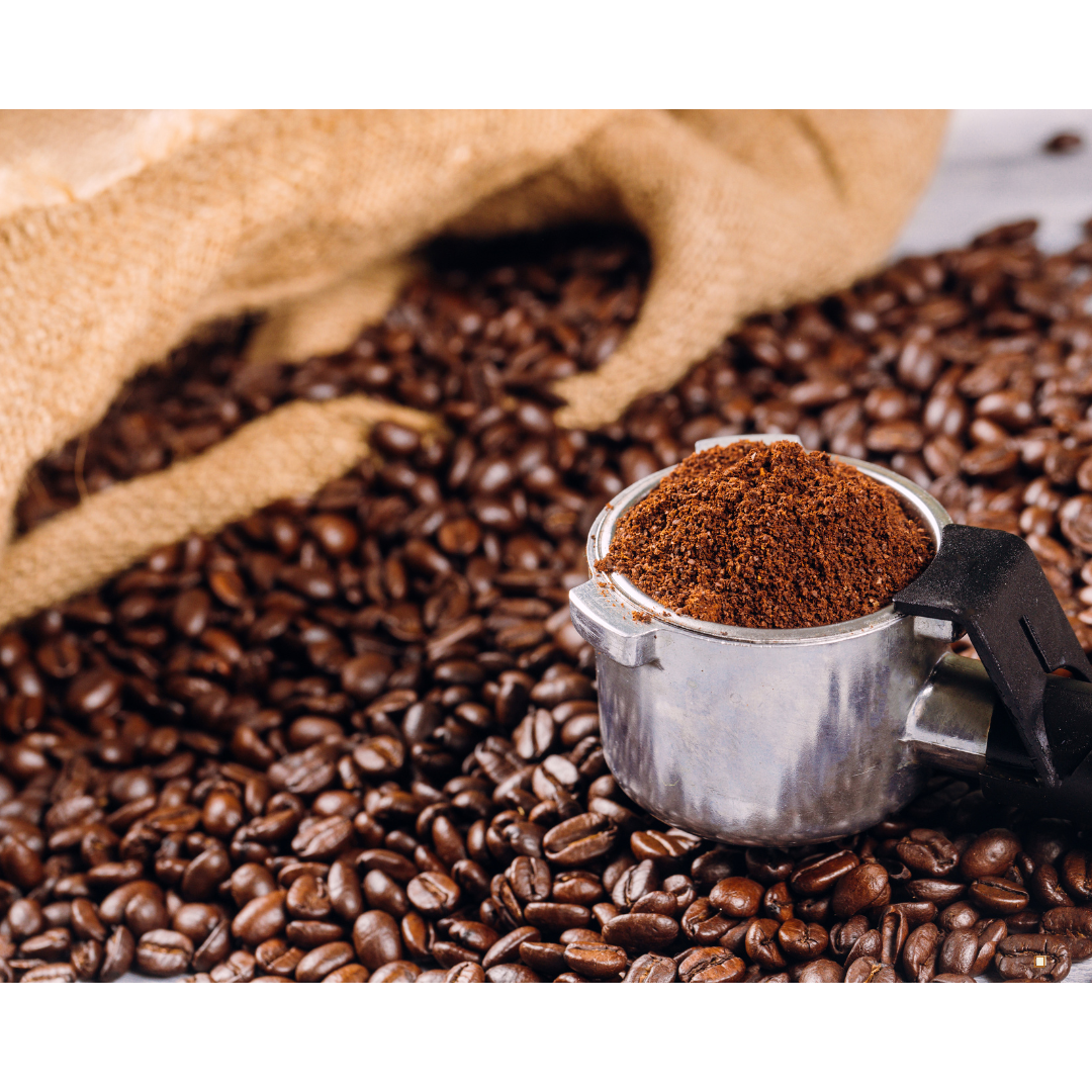 small batch coffee grounds in a scoop surrounded by coffee beans