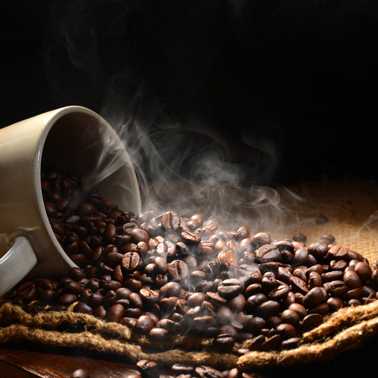 steaming dark roast espresso beans spilled from a cup