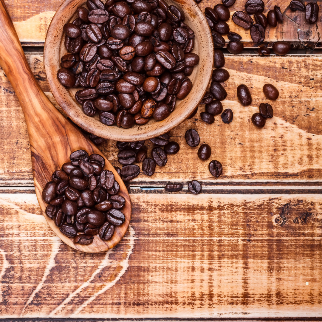 whole bean decaf coffee on a table with spoon and bowl