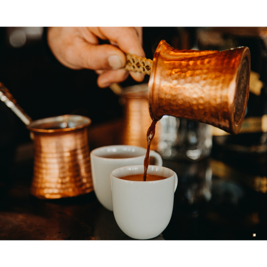 fresh brewed ethiopian yirgacheffe coffee poured from a hammered copper carafe