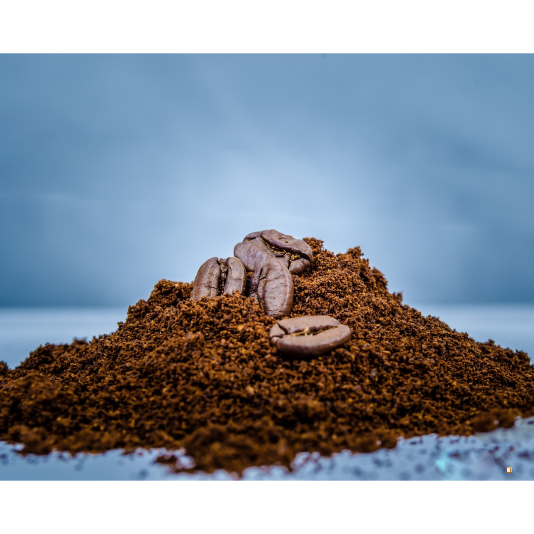 pile of light roast coffee grounds topped by coffee beans