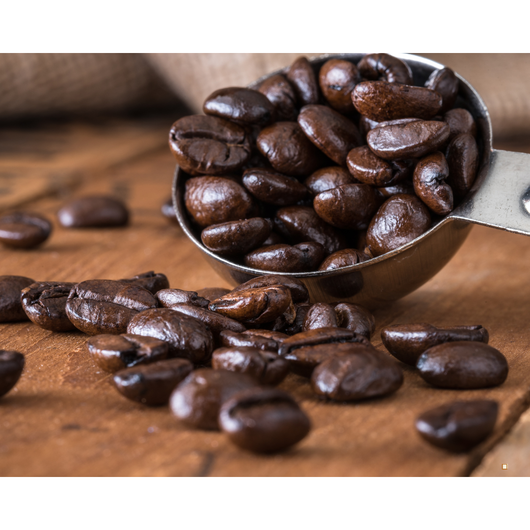 whole bean decaf coffee in a metal scoop on wooden table